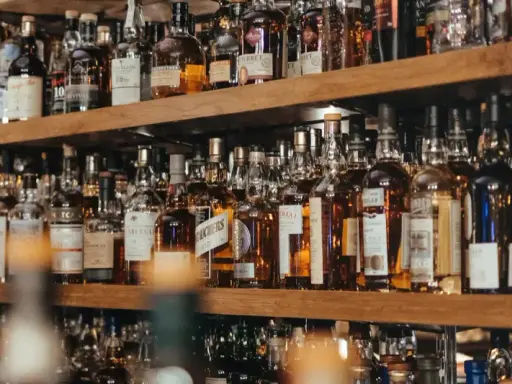 Regale voller Flaschen mit goldbraunem Whisky oder Whiskey. Eine Auswahl für Kenner.