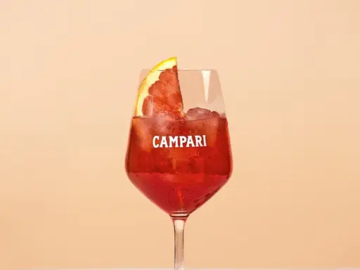 Ein erfrischender Campari Cocktail mit Eis und einer Orangenscheibe, perfekt für einen warmen Abend.