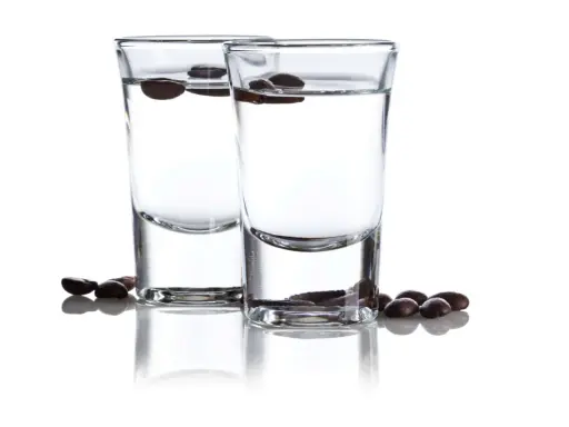 Zwei Gläser mit klarem Schnaps, darin schwimmende Kaffeebohnen. Der Sambuca-Prozent ist hier gut sichtbar.