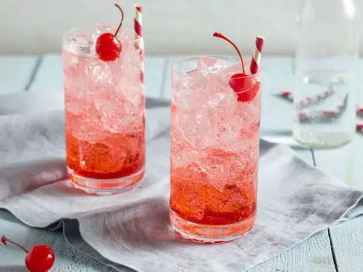 Zwei erfrischende Getränke mit Eis, Kirschen und Strohhalmen. Die rote Farbe verrät, was ist Grenadine: ein süßer Sirup aus Granatäpfeln.