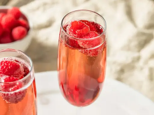 Zwei Gläser Kir Royal mit frischen Himbeeren. Ein einfaches Kir Royal Rezept für besondere Momente.