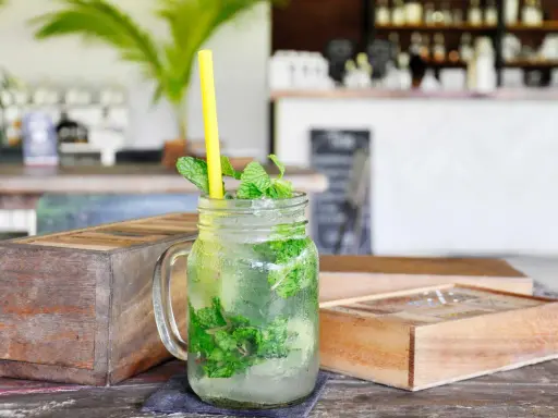 Erfrischender Mojito mit Minze und Eis in einem Glas, dazu ein gelber Strohhalm. Was ist rum? Ein köstlicher Drink!