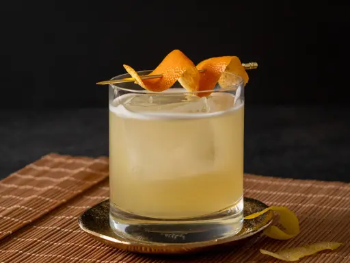 Ein erfrischender Cocktail mit Eis, garniert mit Orangenschale. Für die Süße wurde Zuckersirup verwendet, was ist Zuckersirup? Eine einfache Mischung aus Zucker und Wasser.