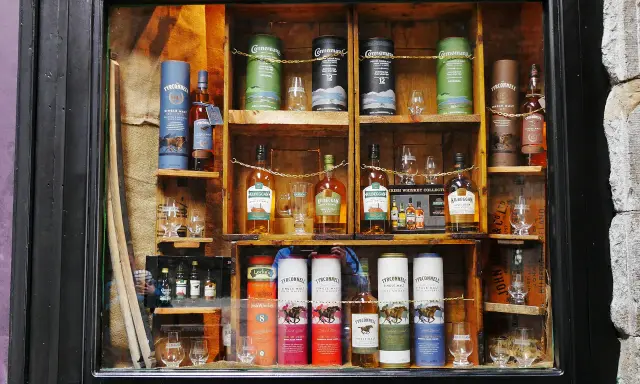 Regale voller Flaschen und Tuben mit irischem Whisky, bereit zum Whisky lagern. Verschiedene Marken wie Tyrconnell und Kilbeggan sind zu sehen.