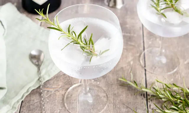 Erfrischender Gin Tonic mit Rosmarin und Eis. Ein Hauch von Kräutern für den perfekten Genuss.
