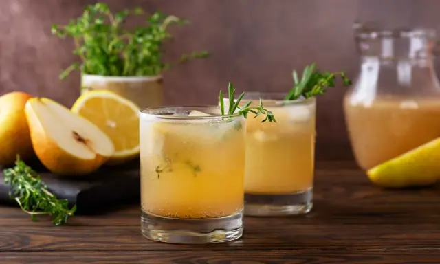 Erfrischender birnen spritz mit Zitrone und Kräutern, serviert mit frischen Früchten und einem Krug des Getränks.