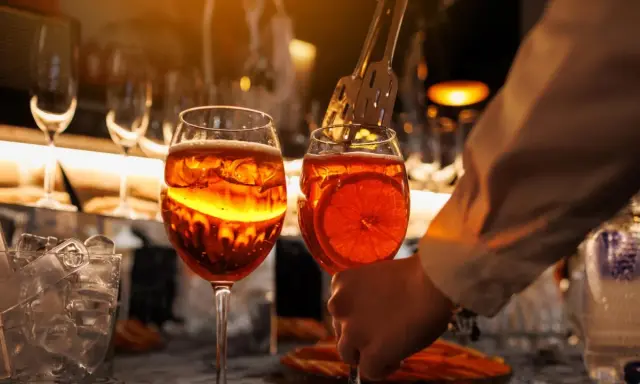 Zwei Aperol Spritz Gläser, bereit zum Genuss. Die leuchtende Farbe erinnert an die Aperol Herkunft in Italien.