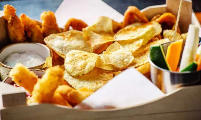Knusprige Kartoffelchips, frittierte Hähnchenteile und Gemüsesticks – ein perfekter Snack, der gut zu Gin passt.