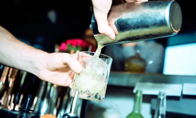 Barkeeper gießt erfrischendes bitter lemon tonic water mit Eis in ein Glas.