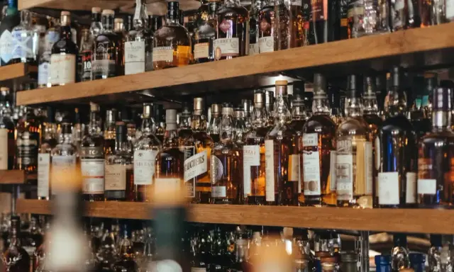 Regale voller Flaschen mit goldbraunem Whisky oder Whiskey. Eine Auswahl für Kenner.