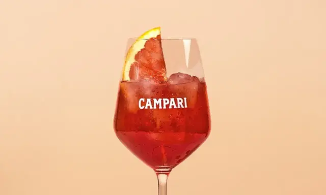 Ein erfrischender Campari Cocktail mit Eis und einer Orangenscheibe, perfekt für einen warmen Abend.