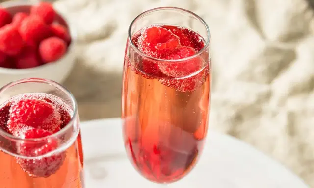 Zwei Gläser Kir Royal mit frischen Himbeeren. Ein einfaches Kir Royal Rezept für besondere Momente.
