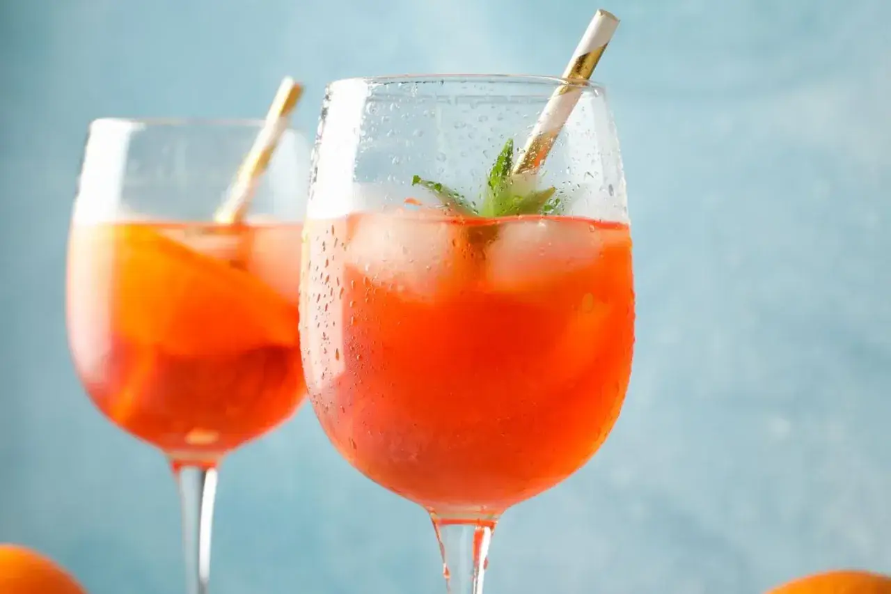 Erfrischendes Aperol Spritz Rezept: Zwei Gläser mit Eis, Orange und Minze, bereit zum Genießen.