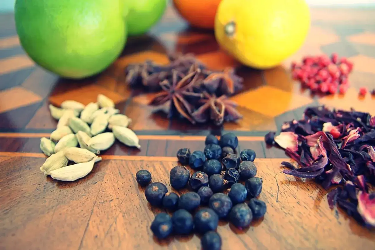Vielfalt an **Gin Zutaten**: Wacholderbeeren, Kardamom, Sternanis, Hibiskus und Zitrusfrüchte auf einem Holztisch.
