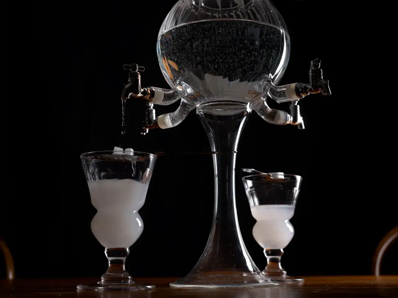 Ein Absinth-Brunnen mit zwei Gläsern, bereit für die Zubereitung. Die Geschichte des Absinth-Ursprungs wird hier lebendig.
