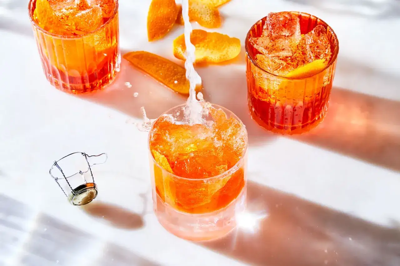 Erfrischendes Aperol Rezept: Spritziger Aperol wird mit Eis und Orangenschale in Gläser gefüllt.