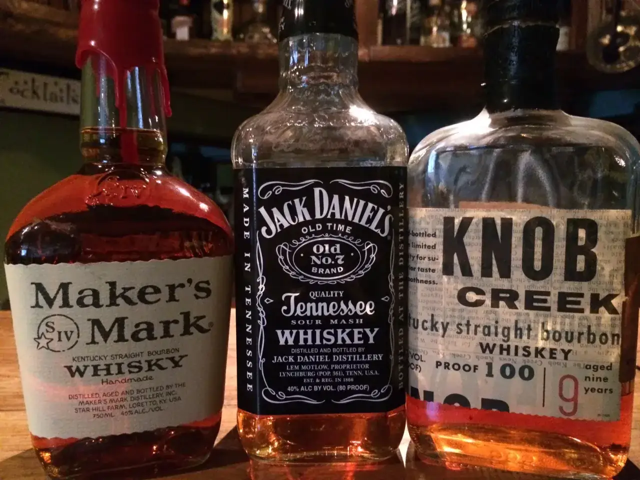 Drei Flaschen Whisky oder Whiskey: Maker's Mark, Jack Daniel's und Knob Creek stehen nebeneinander.