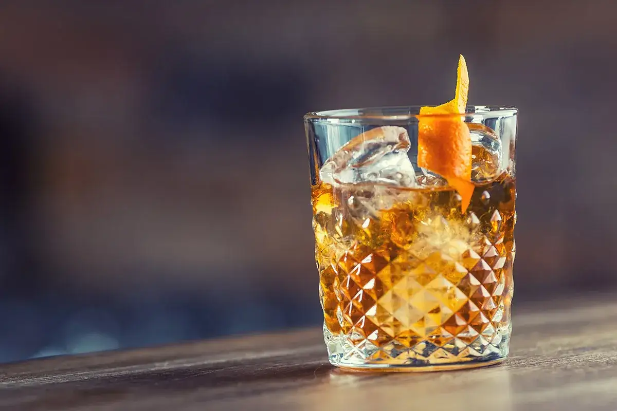 Ein Glas mit Eiswürfeln und einem Spritzer Orangenschale. Perfekt, um einen guten Whisky mit Eis zu genießen.