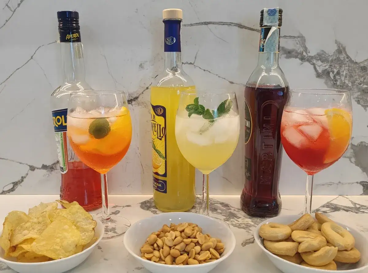 Aperol Spritz, Limoncello und Martini Rosso mit Snacks. Aperol besteht aus Rhabarber, Enzian, Chinarinde und Bitterorangen.