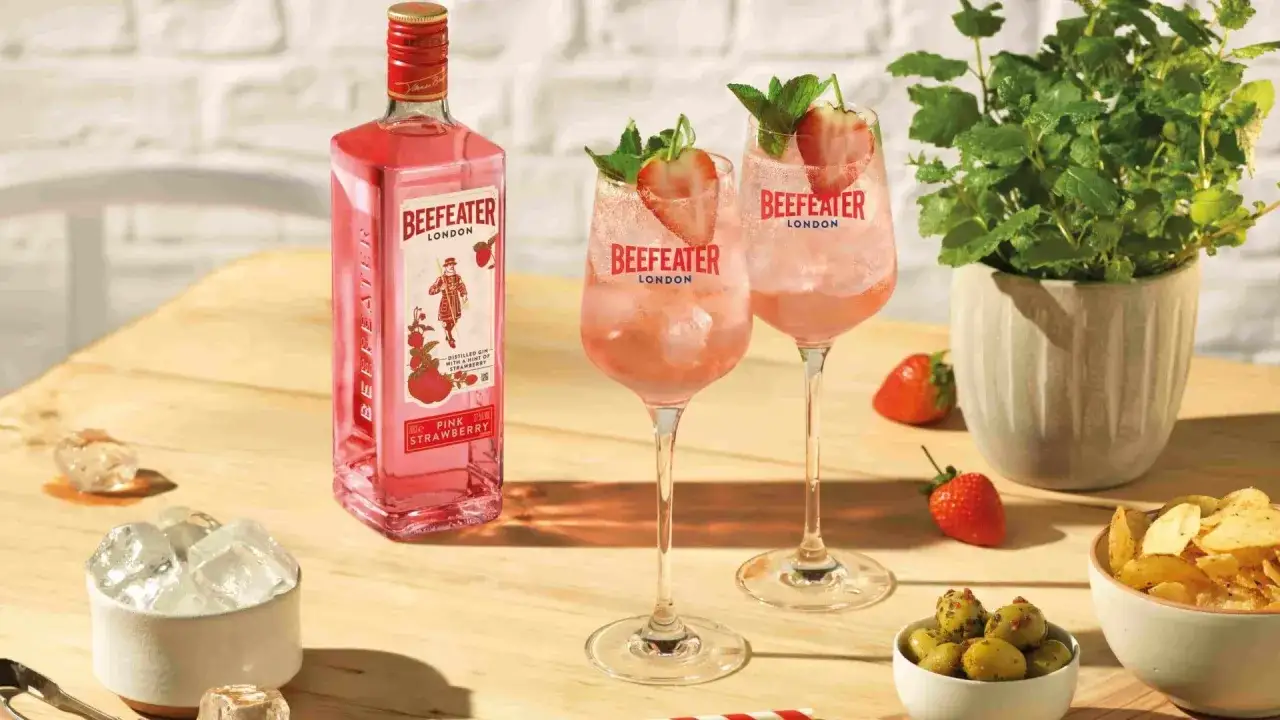 Zwei erfrischende Gin Tonic Aperitifs mit Erdbeeren und Minze, daneben eine Flasche Beefeater Pink Gin. Perfekt für den Sommer!