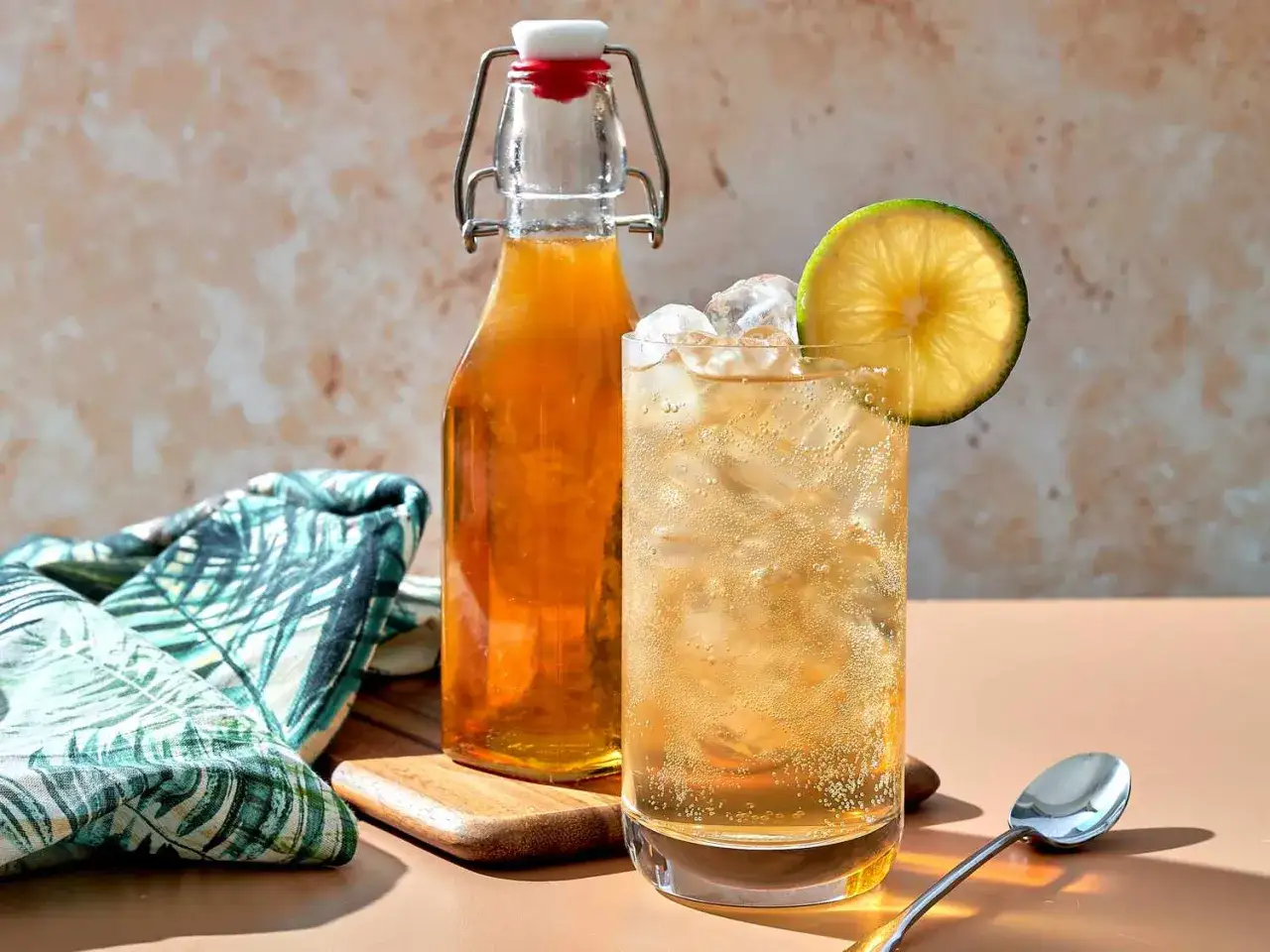 Erfrischendes Getränk mit Eis und Limettenscheibe, daneben eine Flasche mit bernsteinfarbener Flüssigkeit. Das ist, was Tonic Water ausmacht: prickelnd und lecker.