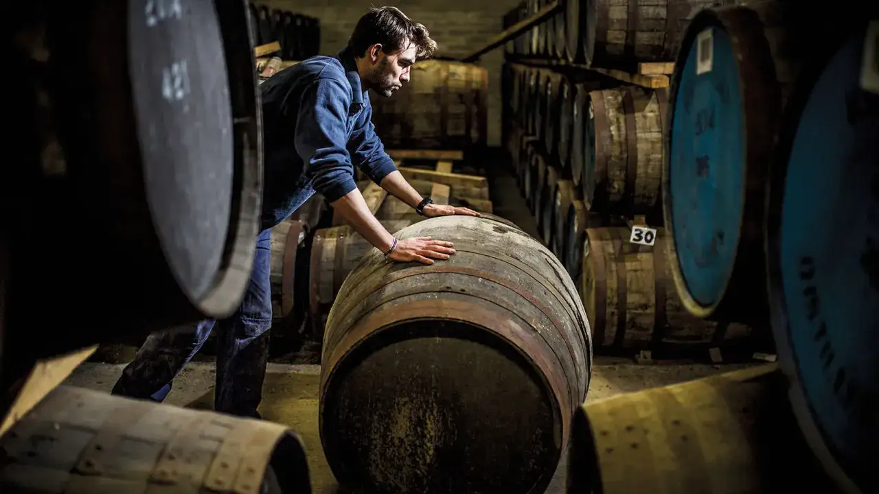Ein Mann berührt eine Holzfass, in dem der schottische Whisky reift.