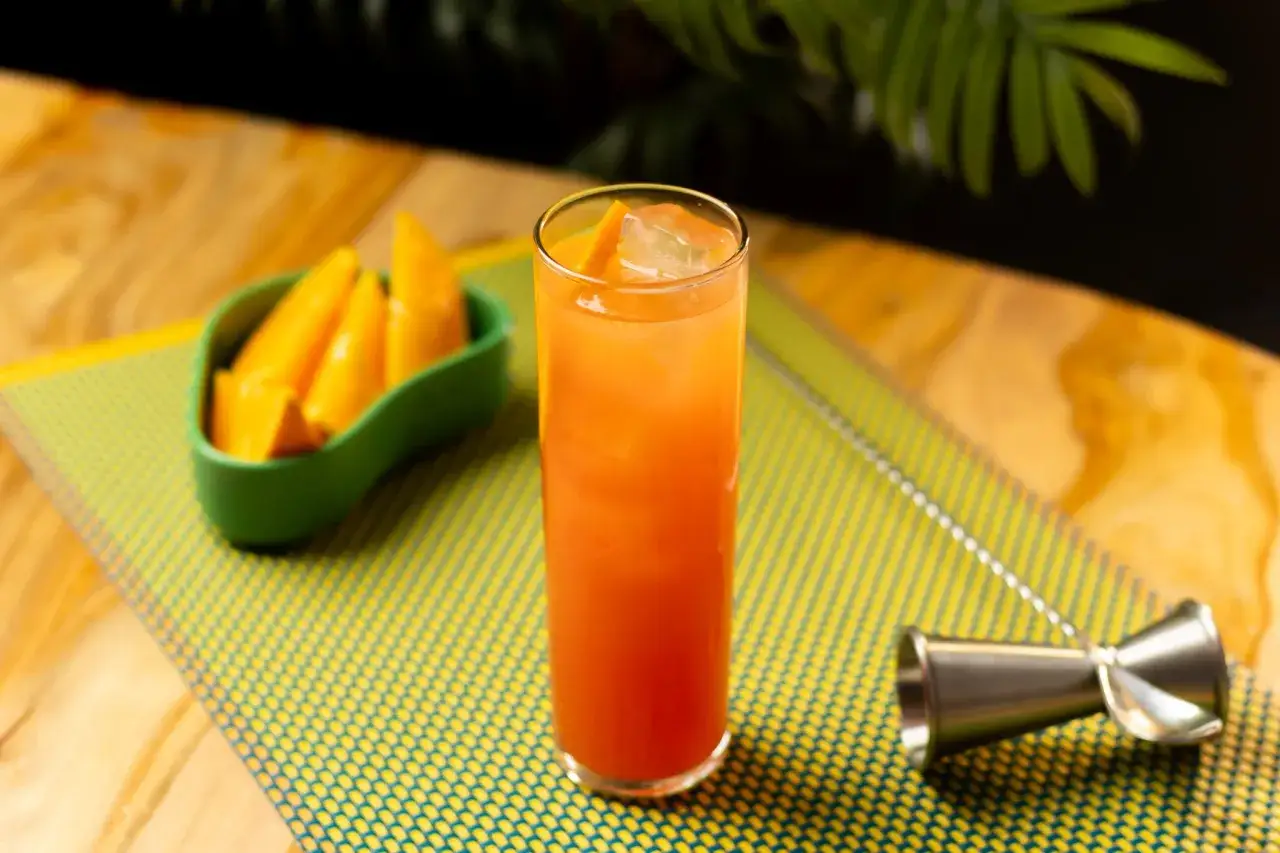 Erfrischender Campari Orange mit Eis und Orangenspalten, daneben eine Schale mit Mangost&uuml;cken.