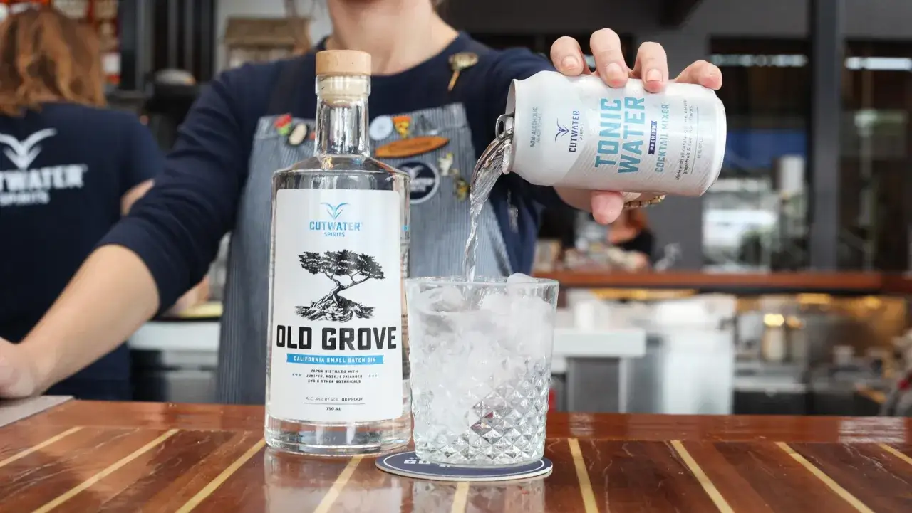 Ein Barkeeper gießt Tonic Water in ein Glas mit Eis. Das Tonic Water enthält Chinin, perfekt für Cocktails.