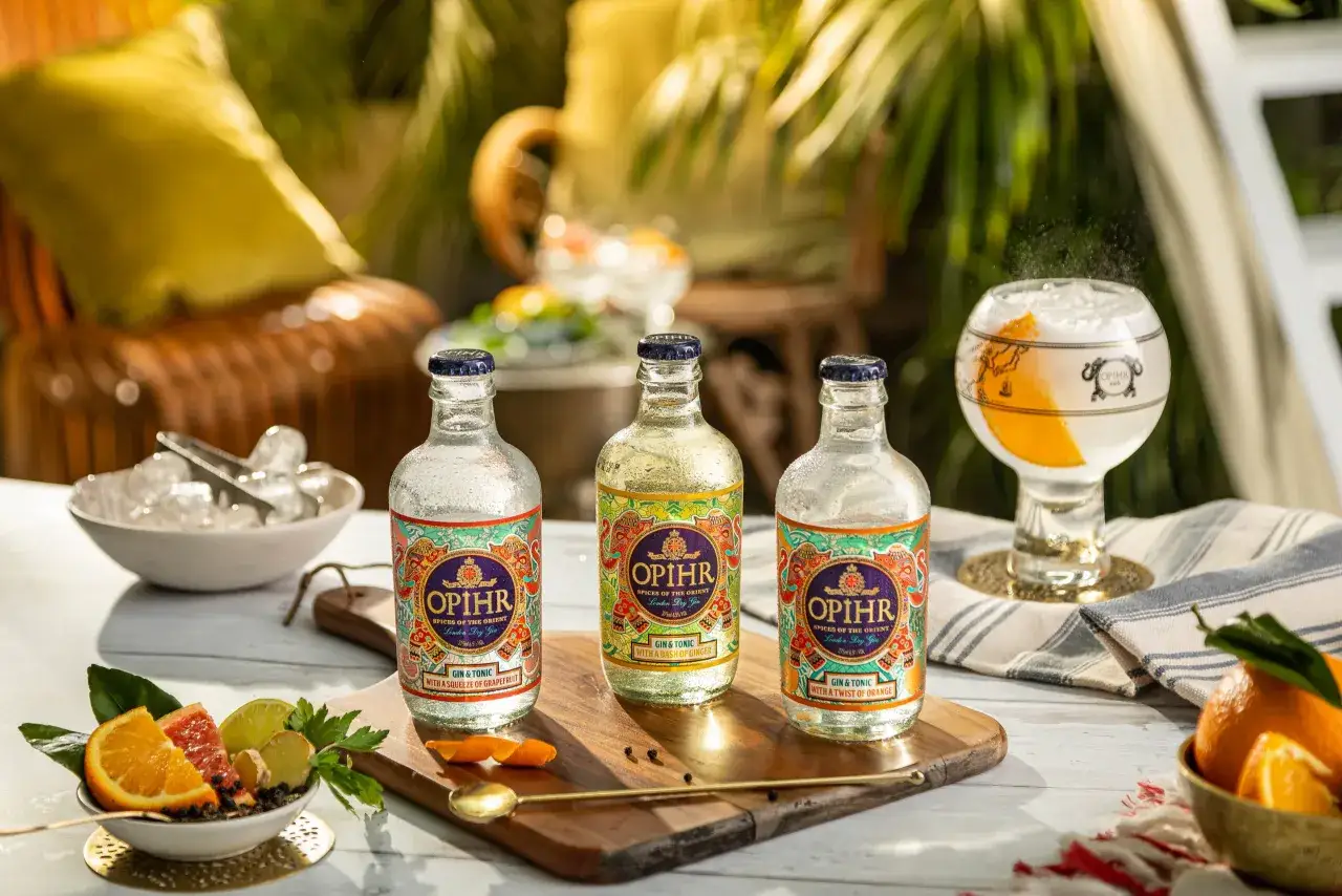Drei Flaschen Opihr Gin & Tonic mit Zitrusfrüchten und Ingwer, bereit für einen erfrischenden Genuss.