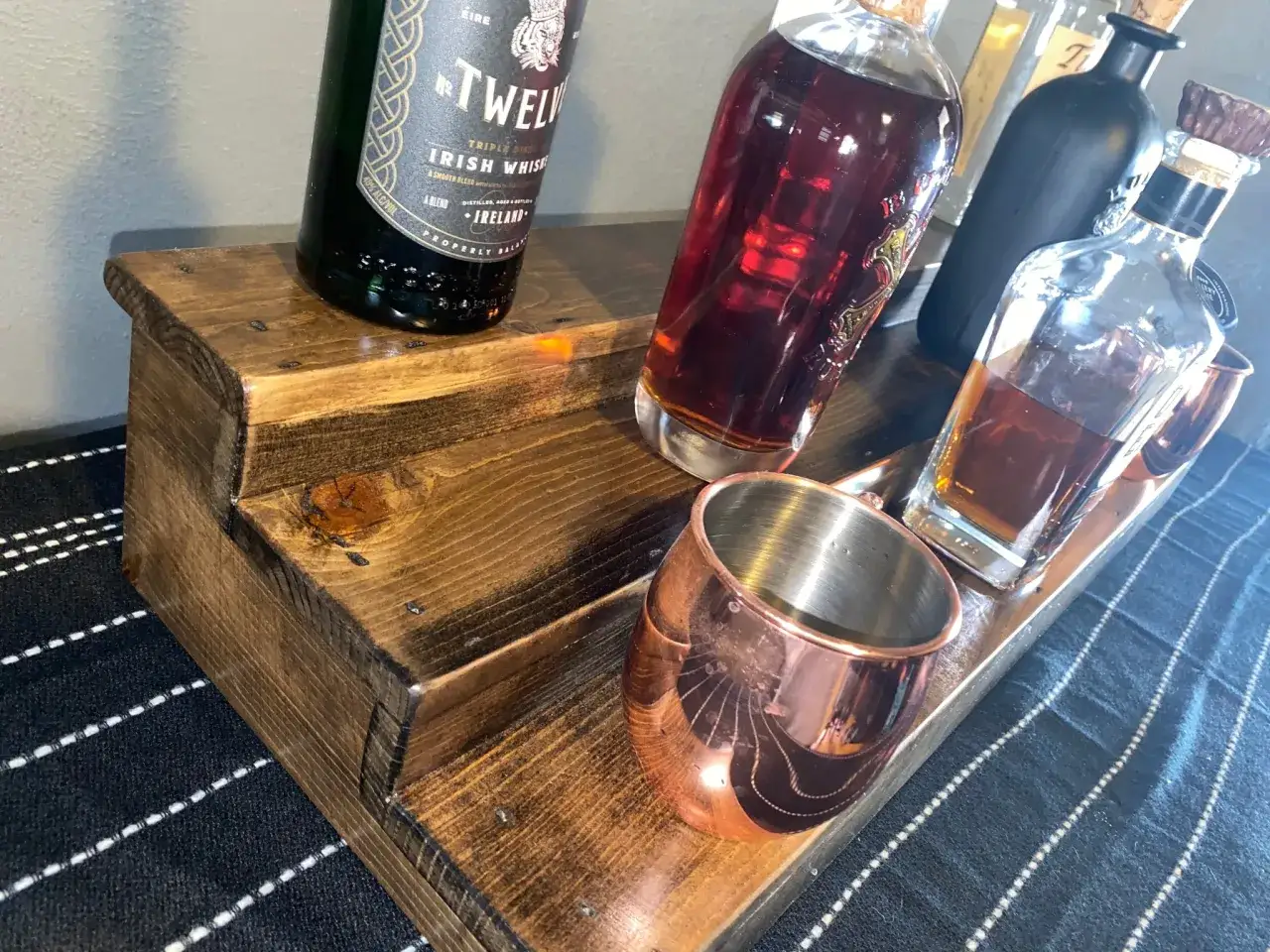 Flaschen mit Whiskey auf Holzdisplay. Die Frage, ob kann Whiskey schlecht werden, besch&auml;ftigt Genie&szlig;er. Hier sind einige Flaschen und ein Kupferbecher.