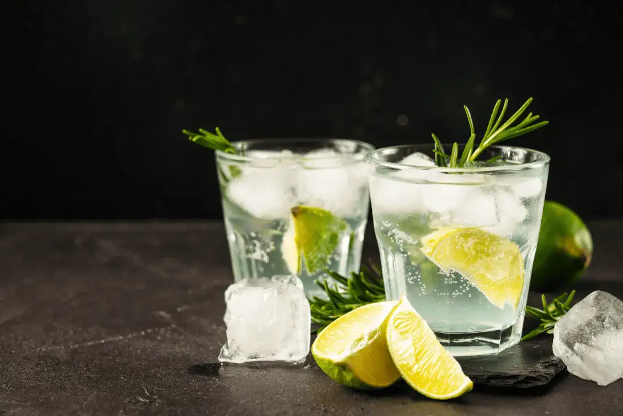 Erfrischendes soda wasser mit Eis, Limettenspalten und Rosmarin in Gläsern.