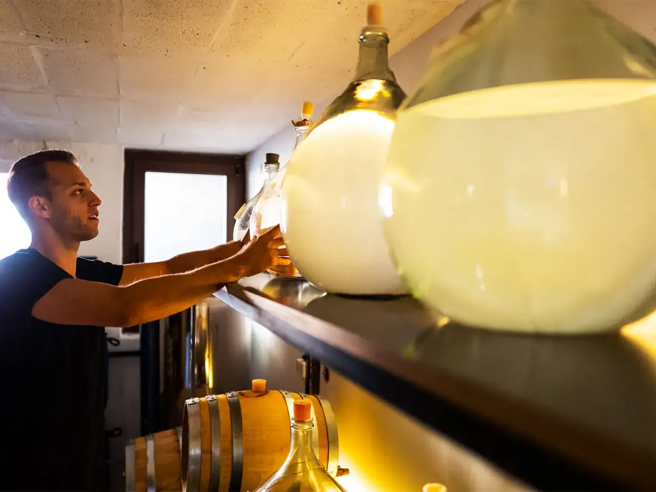 Mann pr&uuml;ft gro&szlig;e Glasballons mit Fl&uuml;ssigkeit. Er achtet darauf, dass nichts von dem Inhalt, der schlecht werden kann, verdunstet.