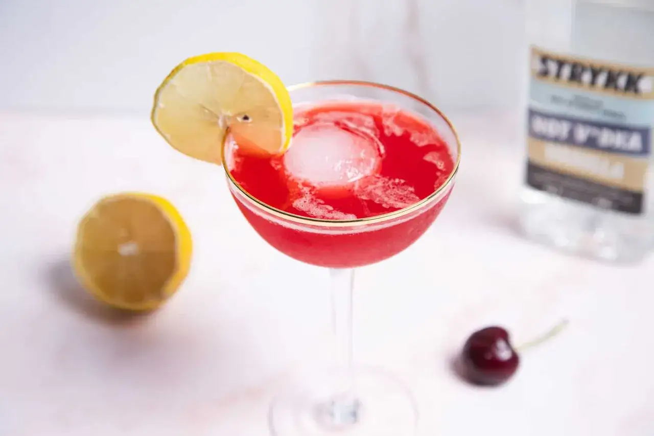 Erfrischender, roter martini alkoholfrei mit Zitrone und Kirsche, daneben eine Flasche 