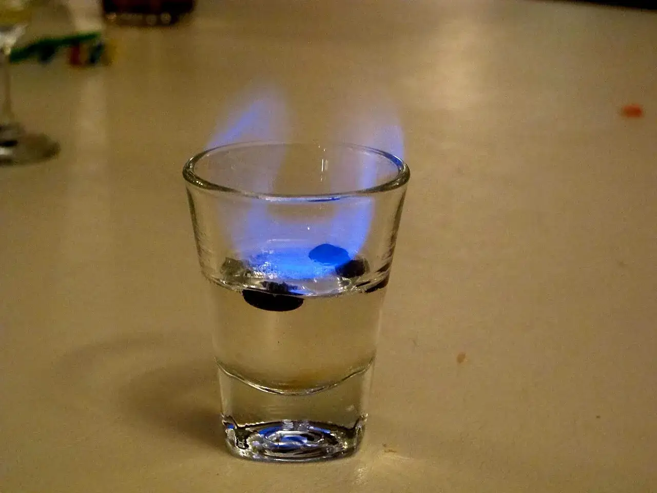 Ein Schnapsglas mit brennendem Sambuca und drei Kaffeebohnen. So trinkt man Sambuca: anzünden, pusten, trinken!