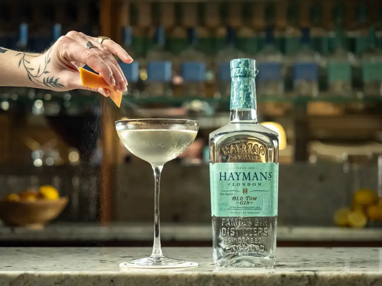 Ein Spritzer Zitrone über einem Glas mit Haymans Old Tom Gin.