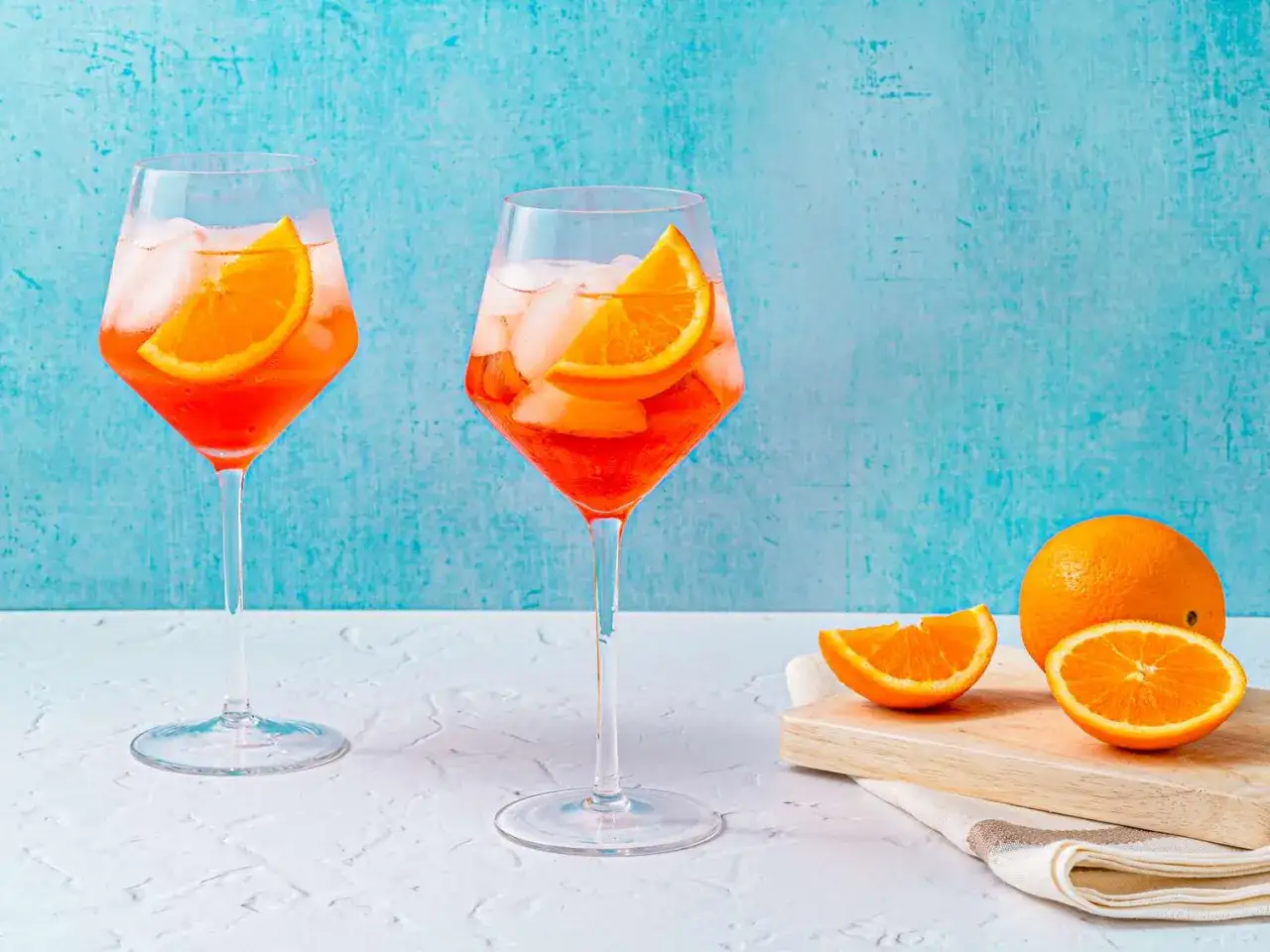 Zwei Aperol Spritz Gläser mit Eis und Orangenscheiben. So schmeckt Aperol Spritz: erfrischend, leicht bitter und fruchtig-süß.