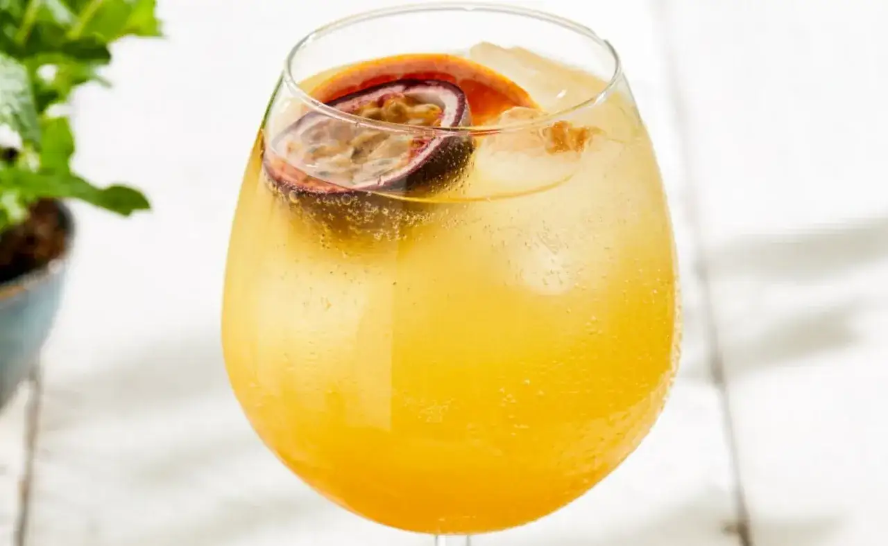 Ein erfrischender Passoa Spritz mit Maracuja und Orange, serviert mit Eiswürfeln in einem großen Glas.