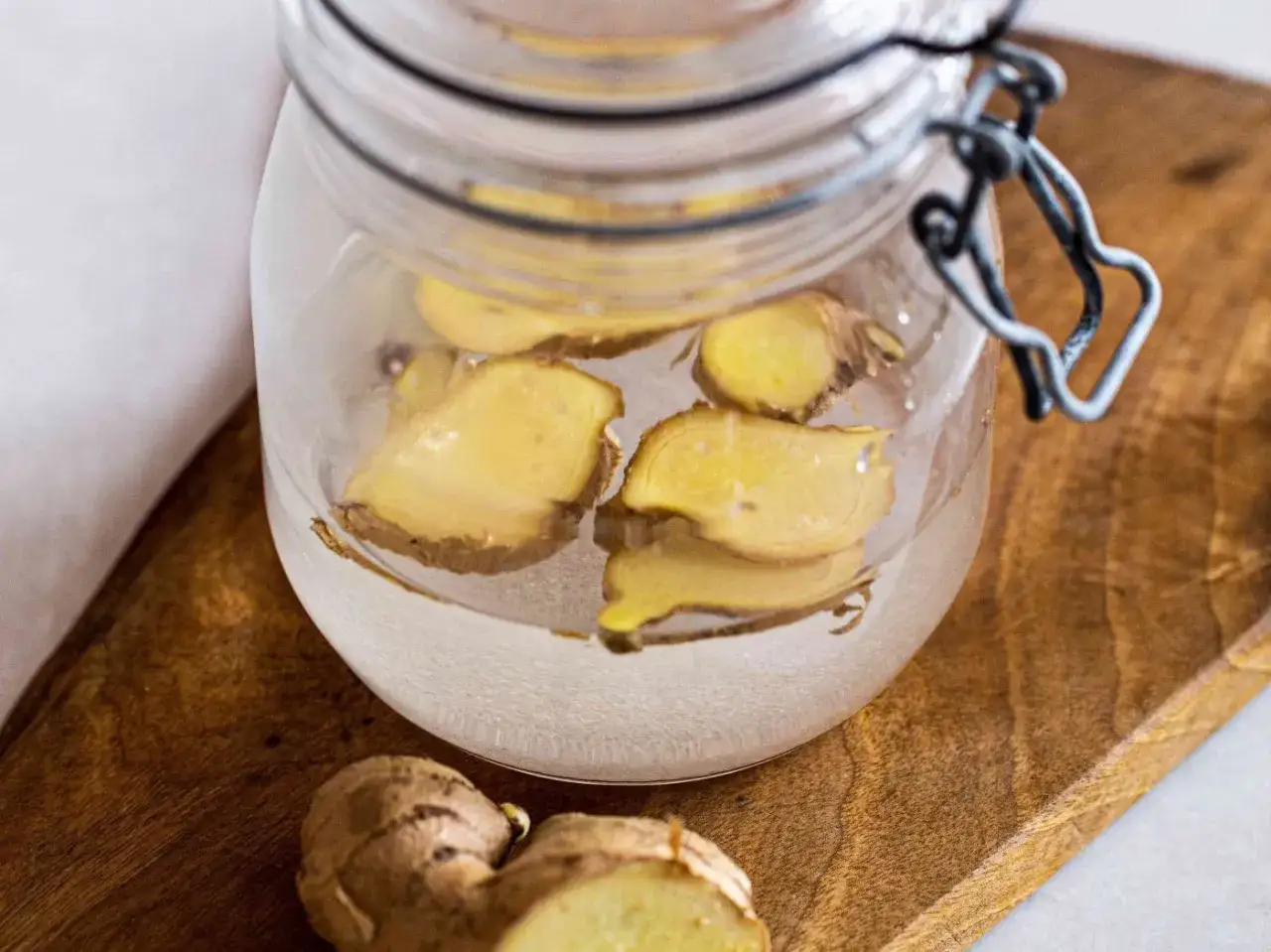 Frische Ingwerscheiben in einem Glas mit Wasser, bereit, um Ginger Beer selber zu machen.
