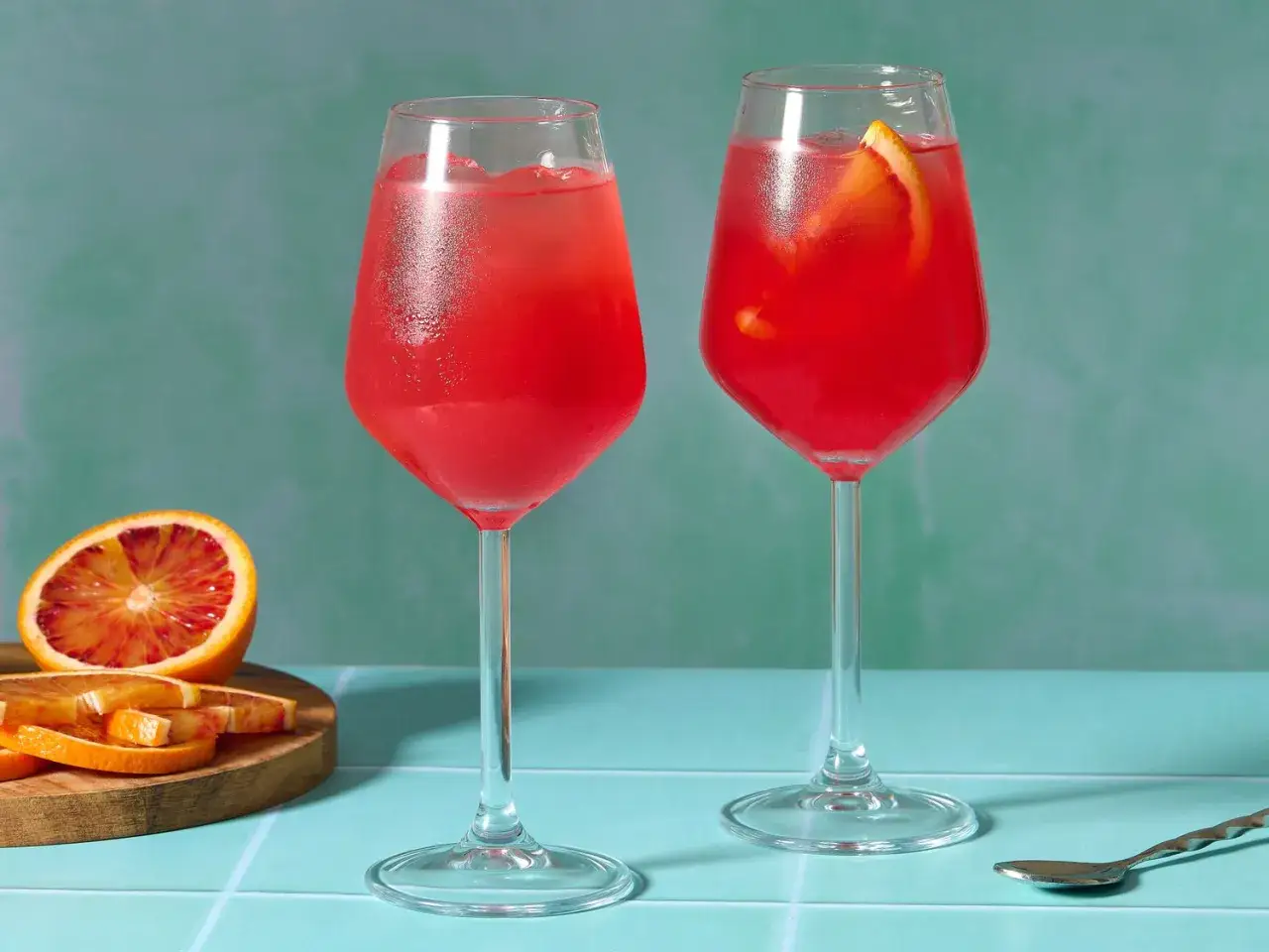 Zwei Gläser mit erfrischendem Aperitif, der an den Campari Geschmack erinnert. Daneben liegen Blutorangenscheiben.