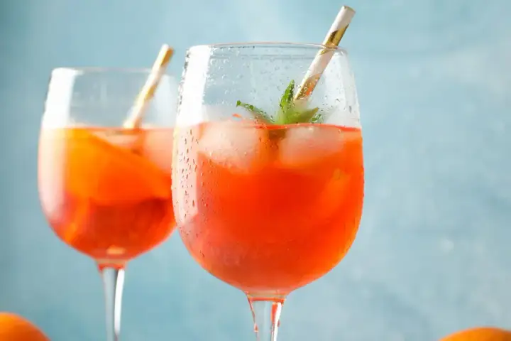 Erfrischendes Aperol Spritz Rezept: Zwei Gläser mit Eis, Orange und Minze, bereit zum Genießen.