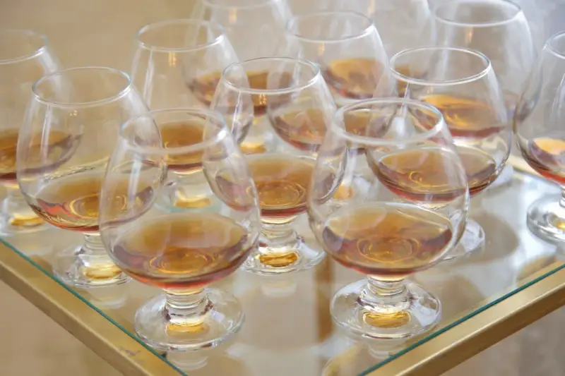 Viele Gläser mit bernsteinfarbenem Metaxa stehen bereit. Was ist Metaxa? Ein griechischer Weinbrand, der nach einer geheimen Rezeptur hergestellt wird.